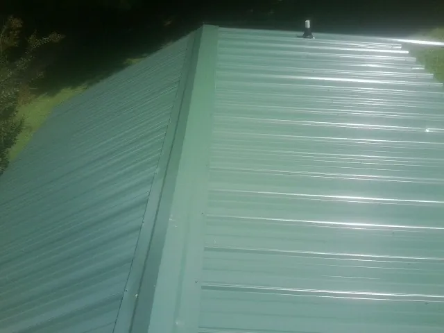 New green metal panels meeting at the ridge of a roof — Flat Roof Repair work by our crew in Rego Park