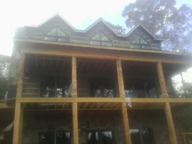 Dormers and porch framing on a large log home under construction — Roof Coating work by our crew in Rego Park