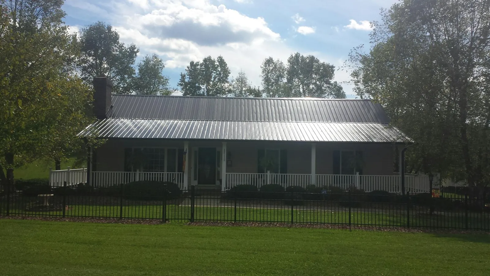 Gray metal roof on a brick ranch with a full width front porch — Gutter Guard Installation work by our crew in Rego Park