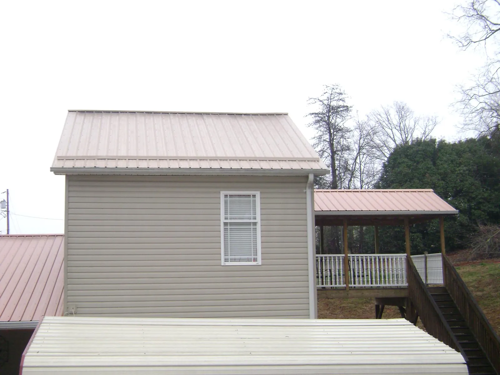 Tan metal roofs on a two story addition and attached porch, from a Roof Replacement job in Rego Park