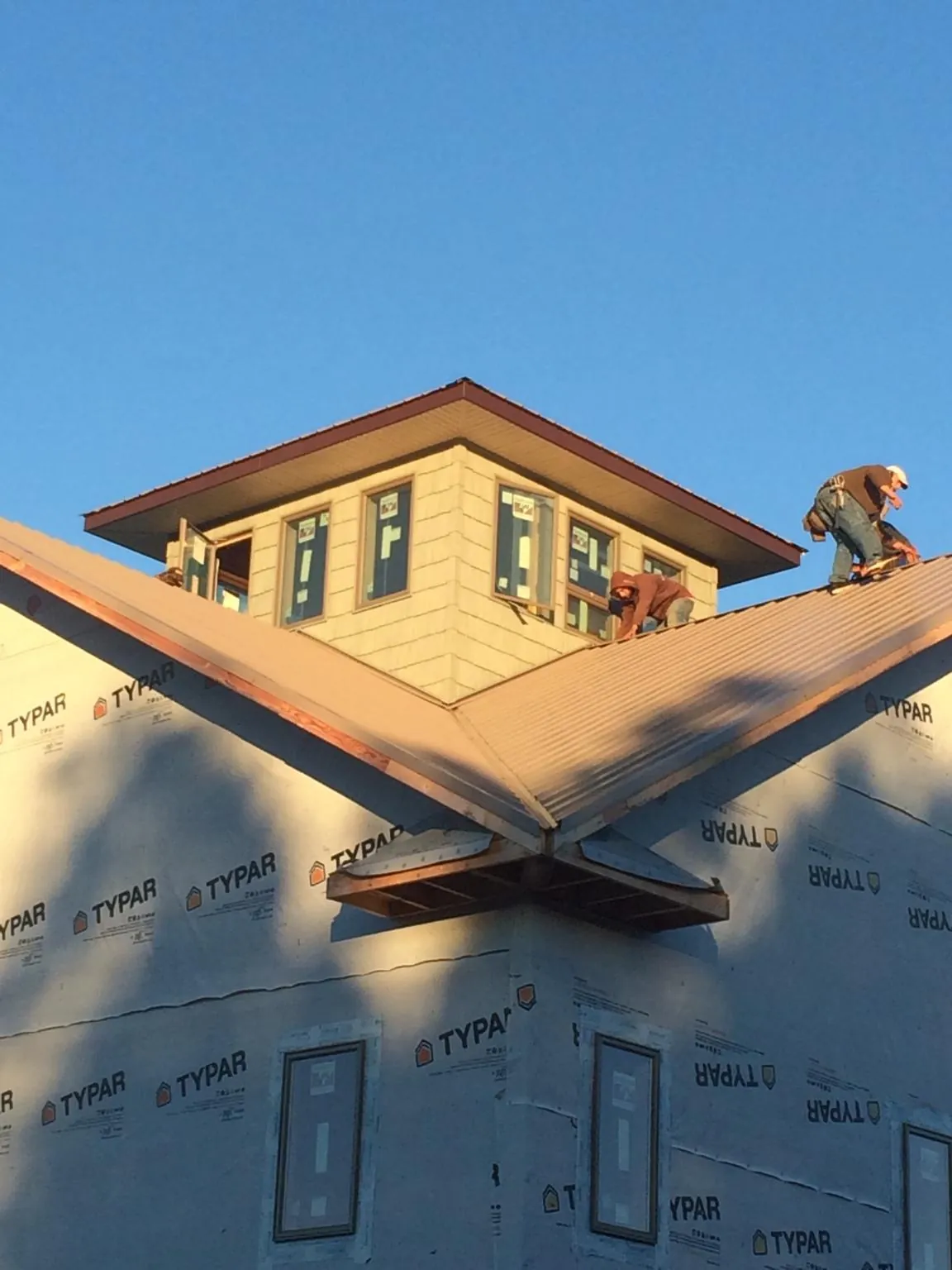 Roofers working around a rooftop cupola on a new metal roof at sunset — Roof Waterproofing in Rego Park by Roofing Brothers